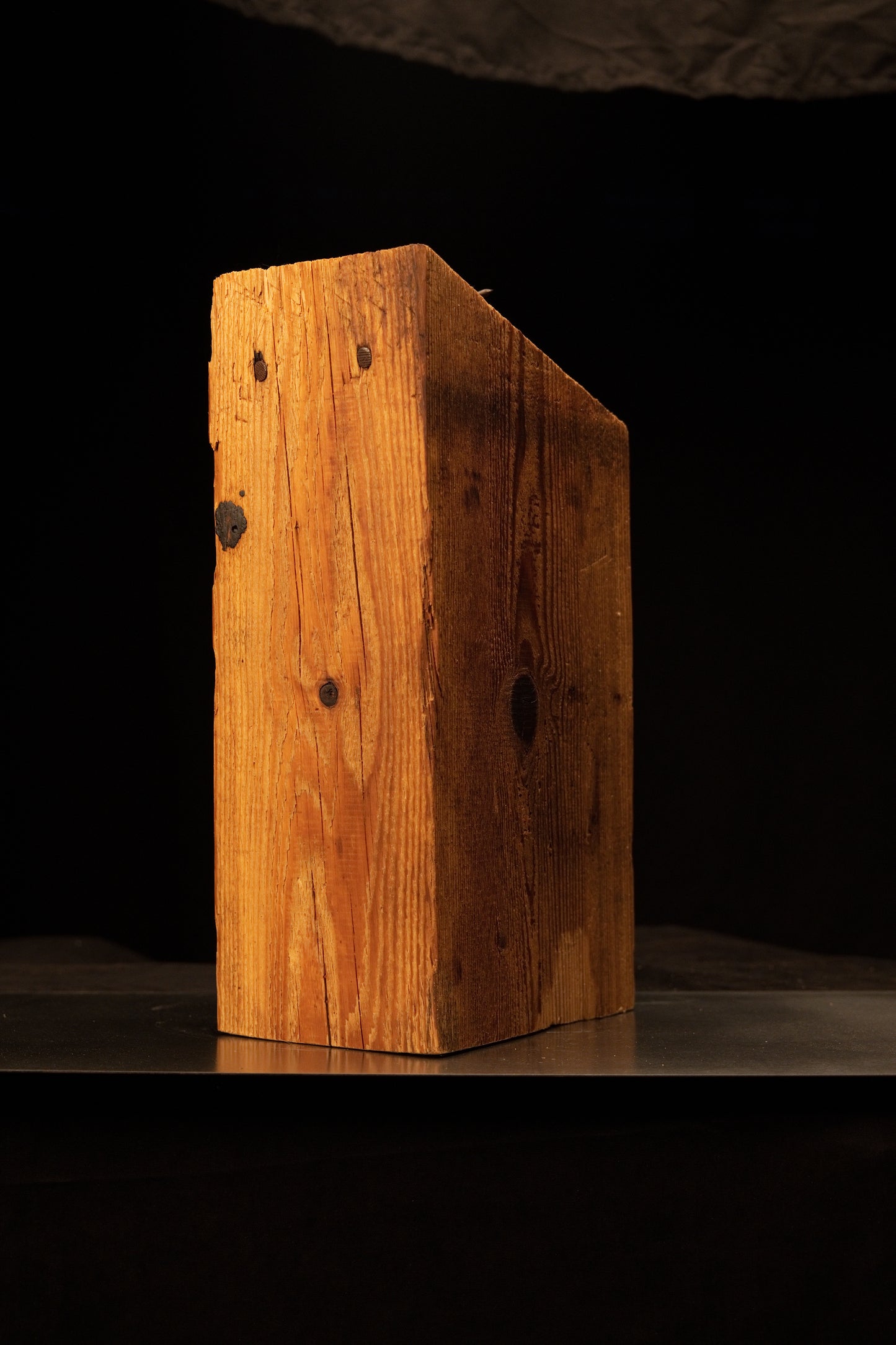 Front view of an architectural salvage structural beam displaying a slanted top cut, golden vertical grain, and dark knot voids.