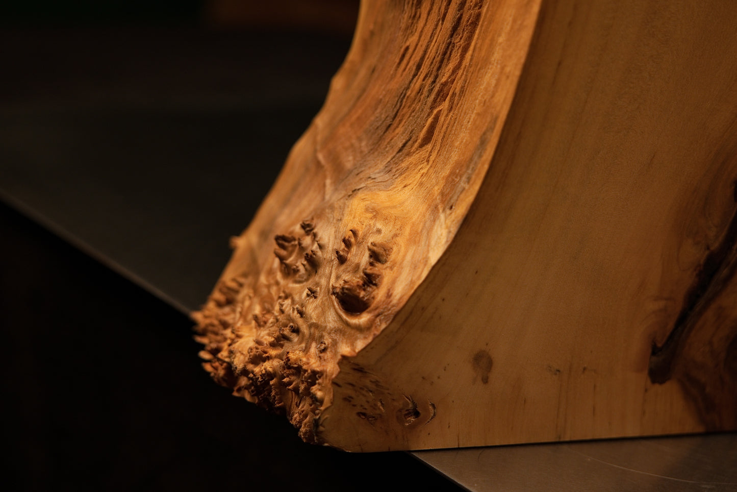 Detailed view of the lower corner juncture where a highly textured burl perimeter meets the pristine flat base of the interior sculpture.