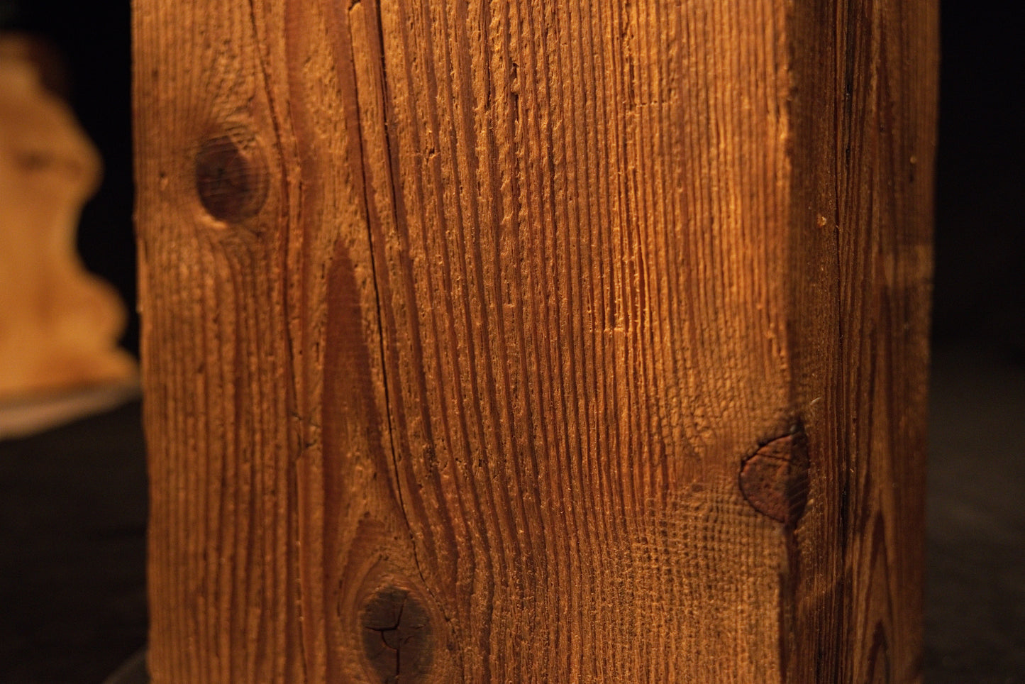 Extreme macro capturing sweeping vertical grain lines curving around a small dark knot on a climate-stable timber piece.