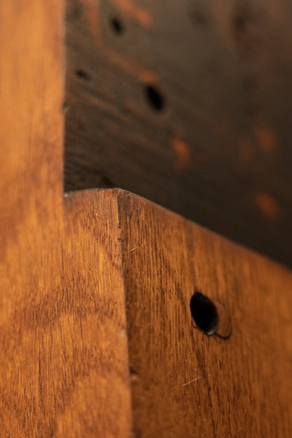 Macro detail of the structural stepped ledge transitioning from dark aged historical patina to raw oak grain. 