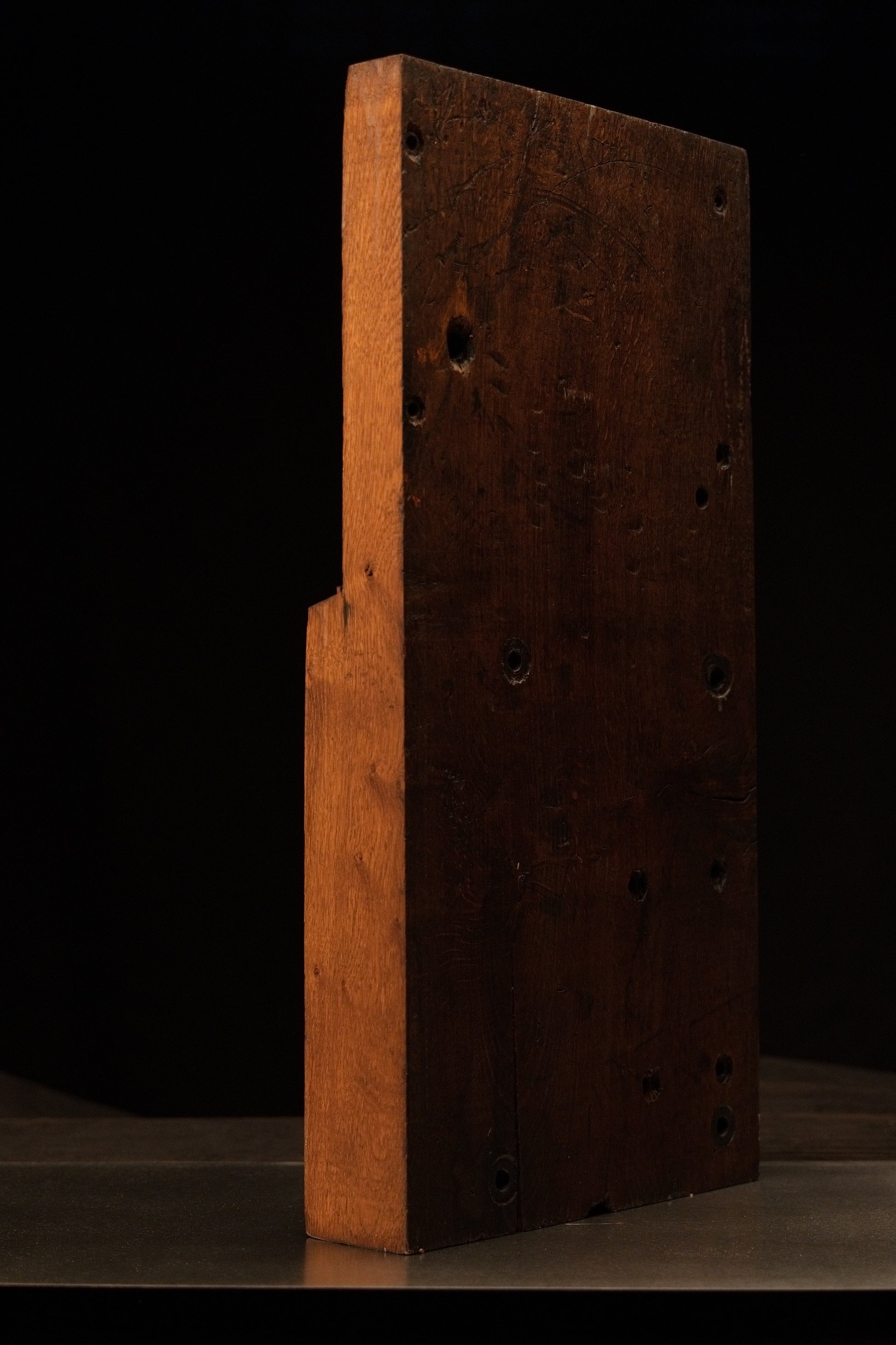 Right side profile of a heavy, two-toned historical architectural timber block featuring structural peg holes and true patina. 