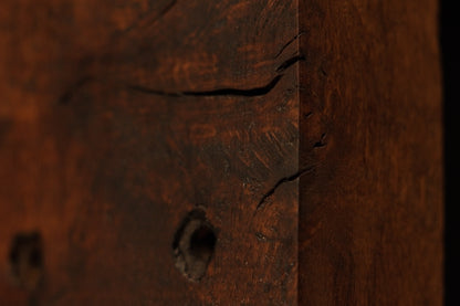 Macro view of the dark architectural salvage wood edge highlighting deep soil mineral absorption and authentic organic patina. 