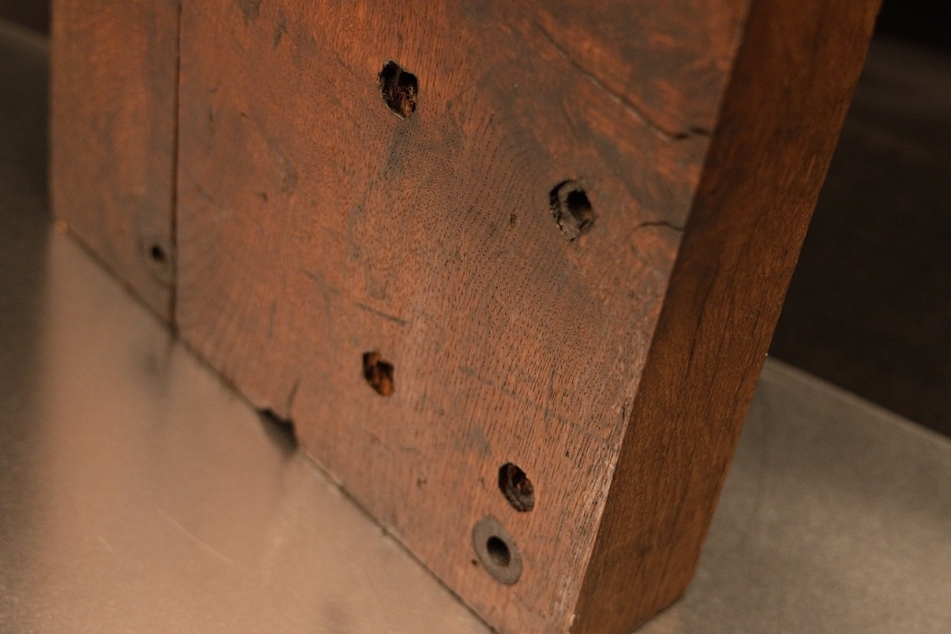 Angled close-up on the lower golden section of the botanical monolith displaying precision historical joinery hole alignments. 
