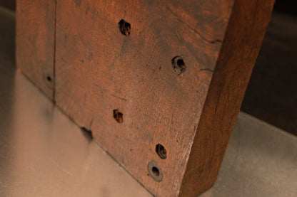 Angled close-up on the lower golden section of the botanical monolith displaying precision historical joinery hole alignments. 