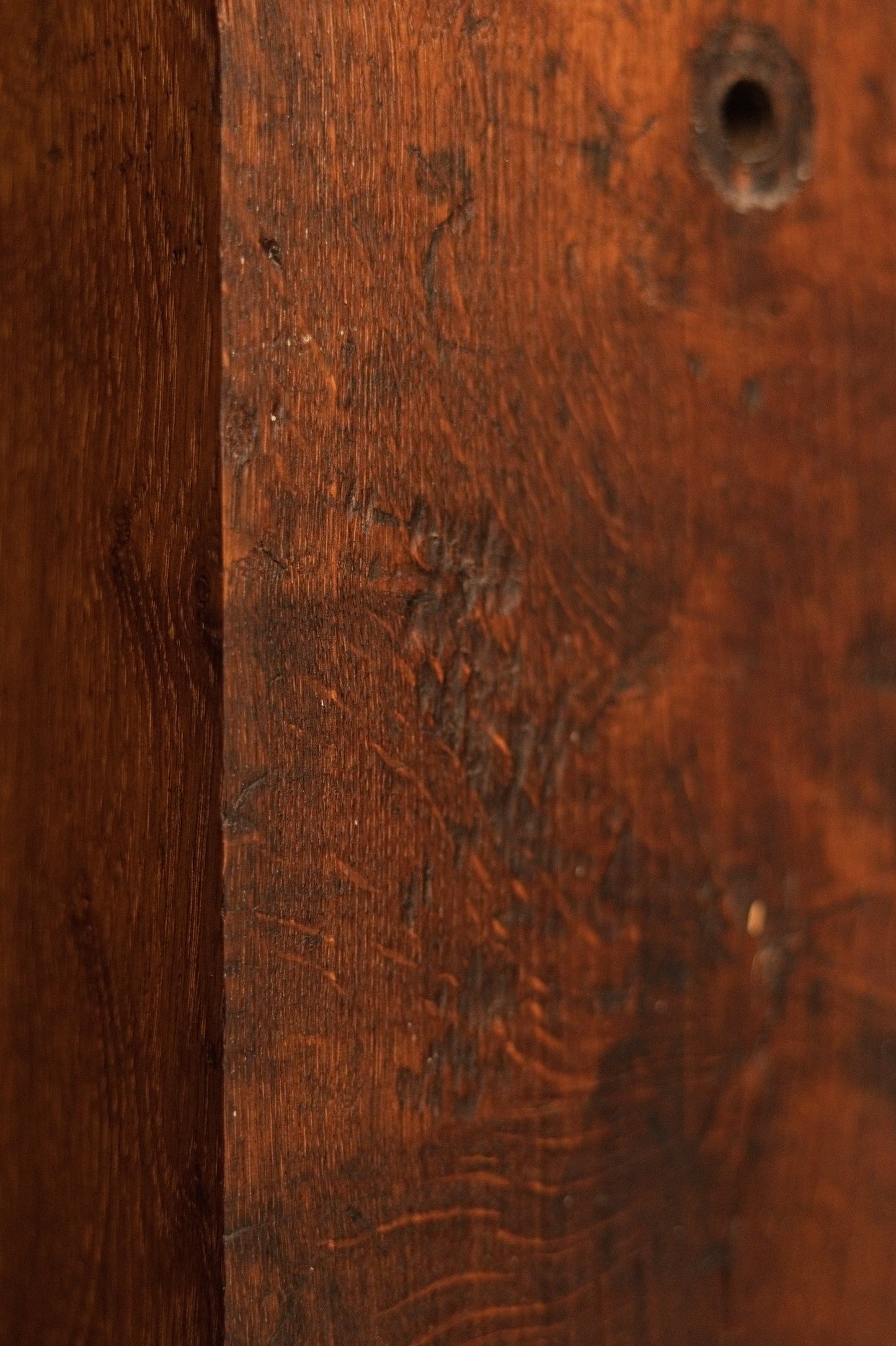 Extreme close-up on the dark oxidized corner of the architectural monolith revealing rich organic textures and true wood patina. 