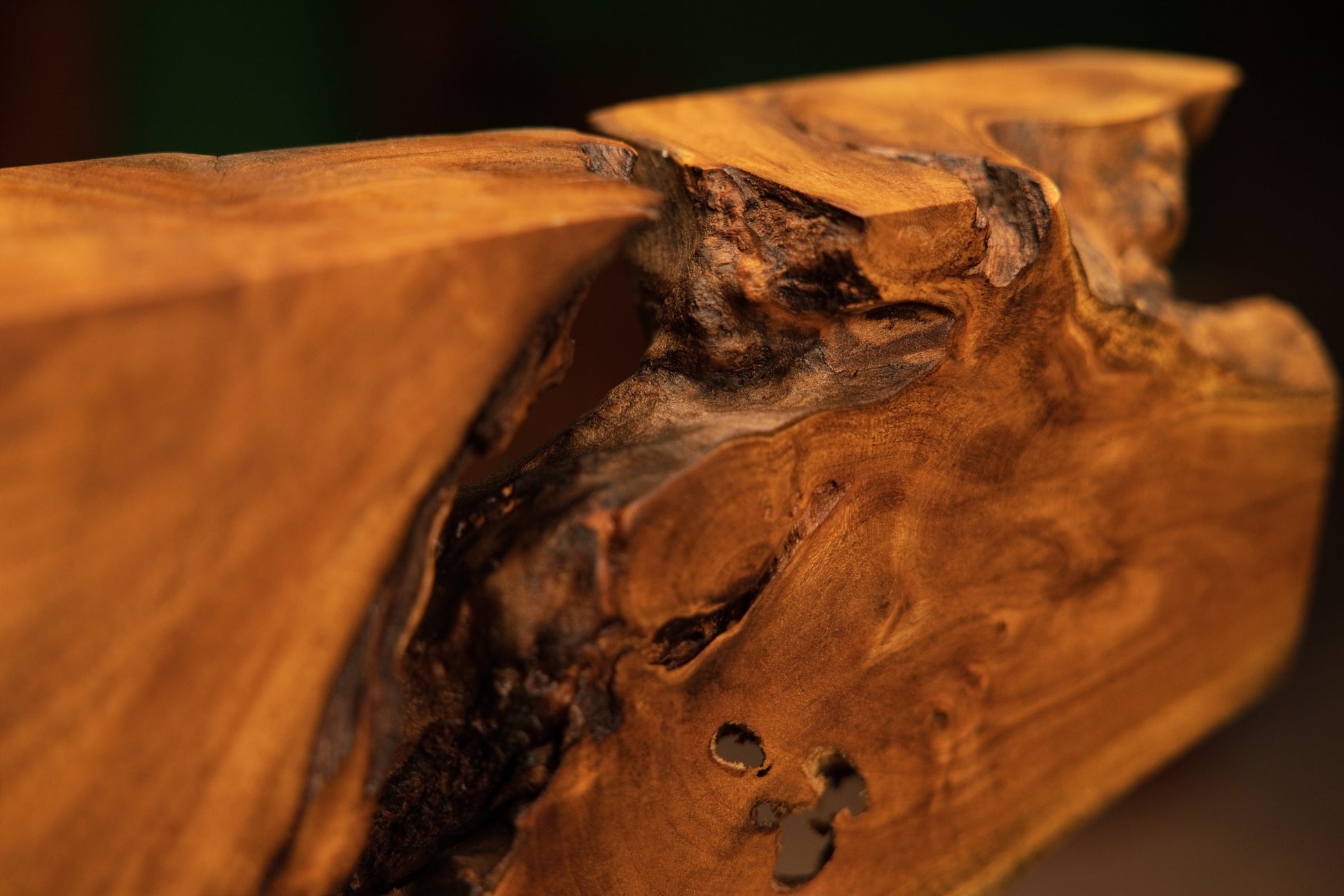 Detailed close-up capturing a deep dark organic cavity intersecting wavy golden-brown wood grain on the medium oak root sculpture.