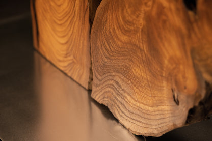 Detailed perspective of the lower right corner where vertical wood grain meets the flat studio base plate on the oak sculpture.