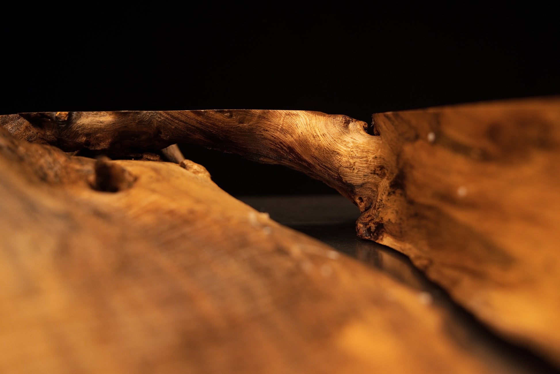 Close-up view of the structural timber intersection showing natural grain continuity across the solid medium oak root sculpture.