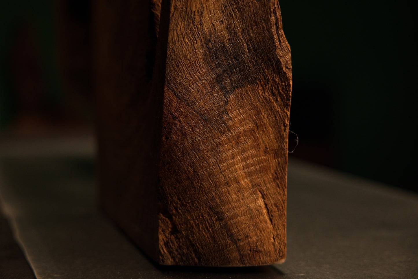 Detailed side profile of a thick-cut solid structural timber slab showing rich grain patterns and dark patinated organic edges.