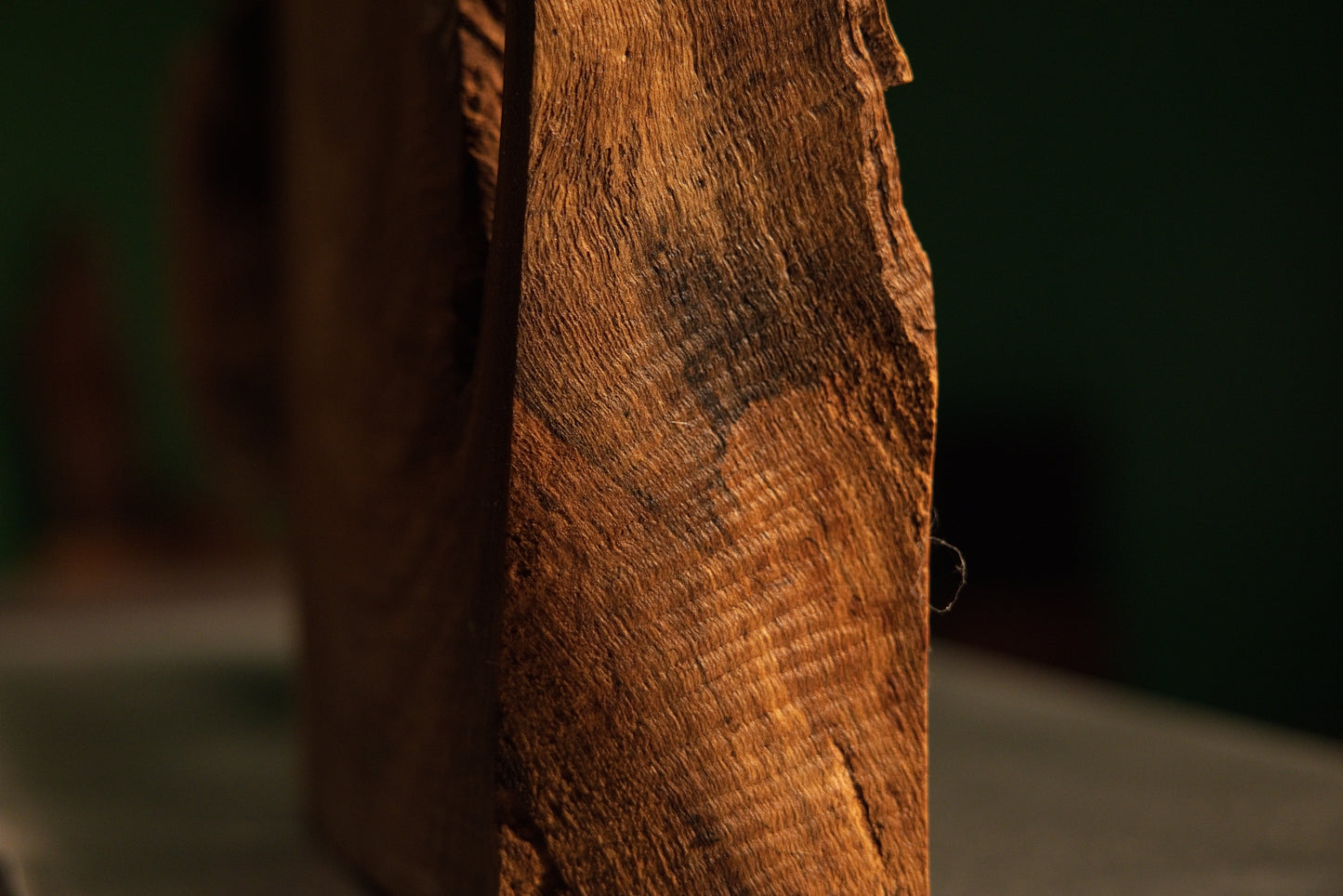 Detailed side perspective of a weathered solid wood block displaying rich golden-brown grain and dark patinated surface features.