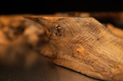 Angled macro view focusing on a weathered wooden block corner featuring a dark natural knot and rough fibrous end-grain texture.