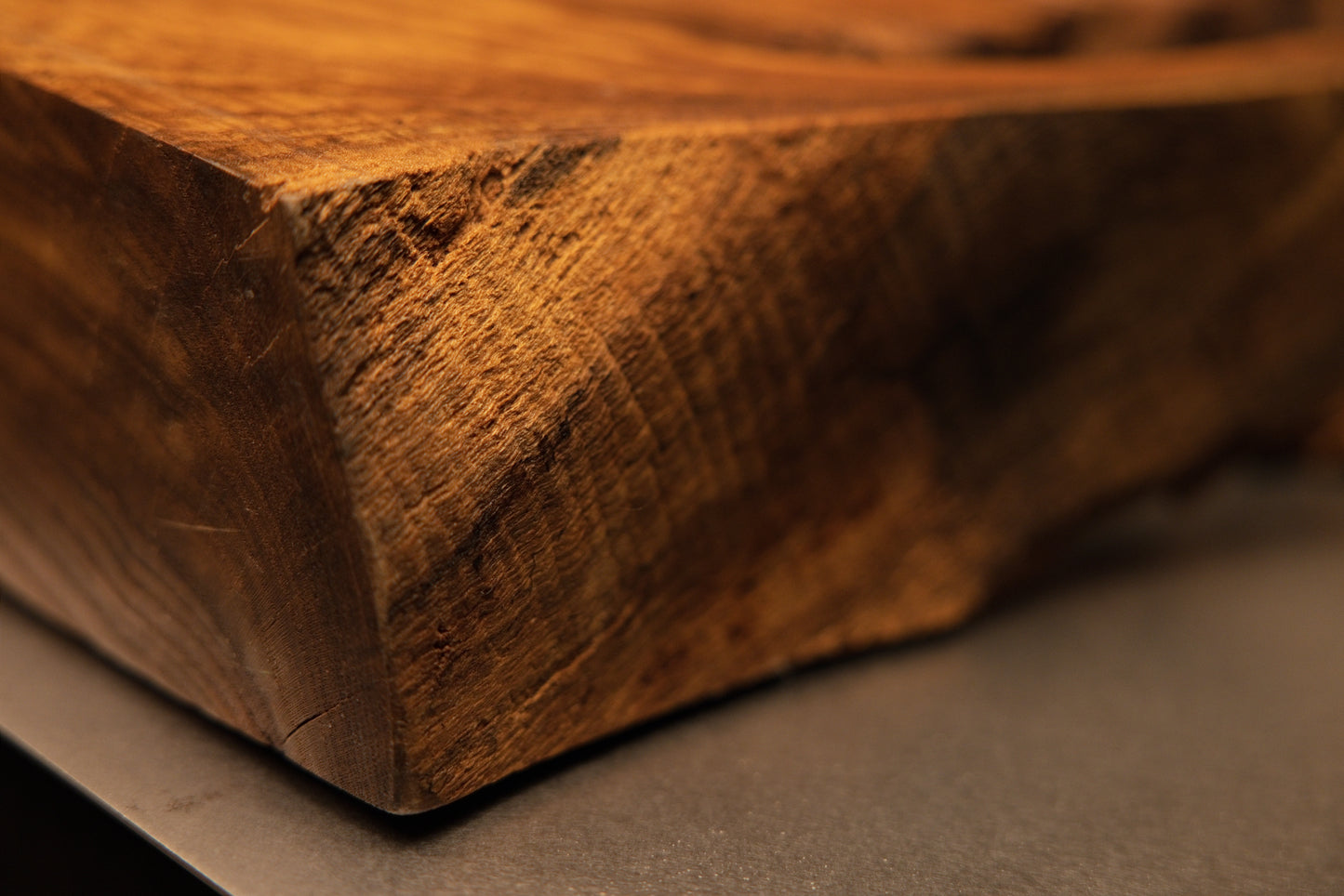 Angled macro shot of a solid wooden block corner showing precision cut angles and rich golden-brown grain textures on the artifact.