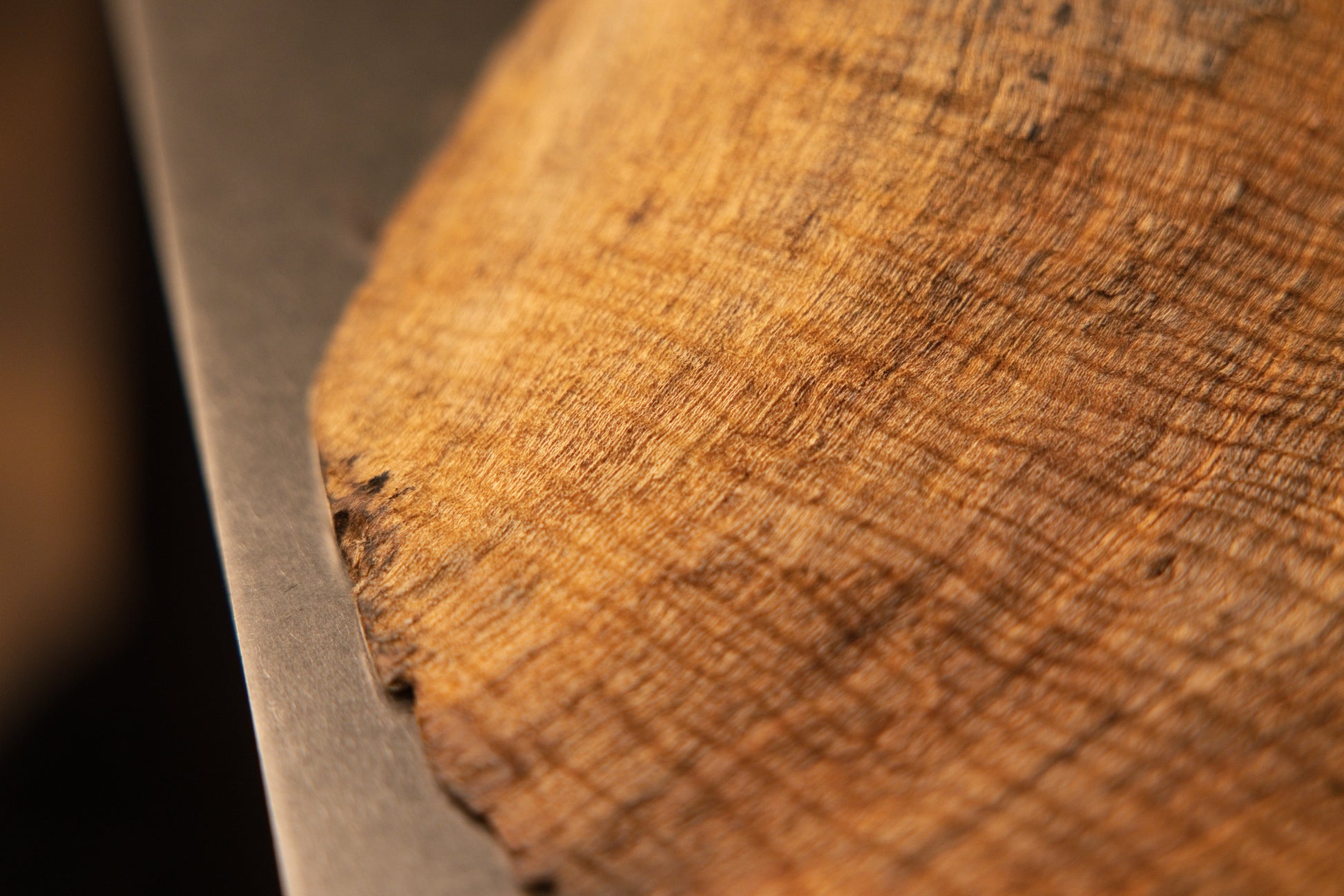 Macro view focusing on a fine fibrous wooden texture with delicate cross-grain patterns near the lower base edge of the sculpture.