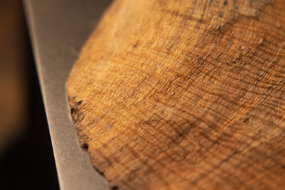 Macro view focusing on a fine fibrous wooden texture with delicate cross-grain patterns near the lower base edge of the sculpture.