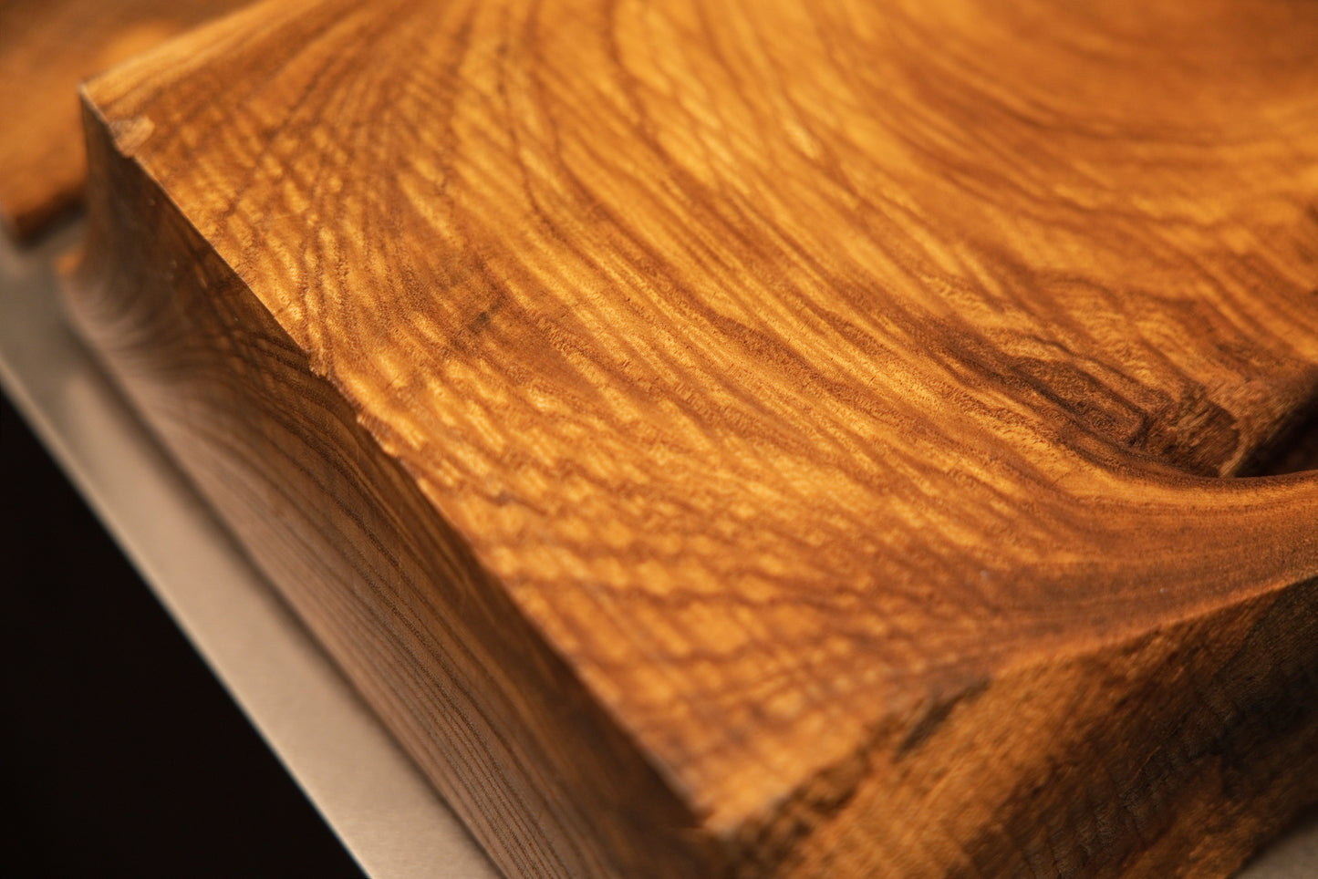 Angled macro view of a solid wooden corner block showcasing rich textured cross-grain details and a warm amber polished finish.