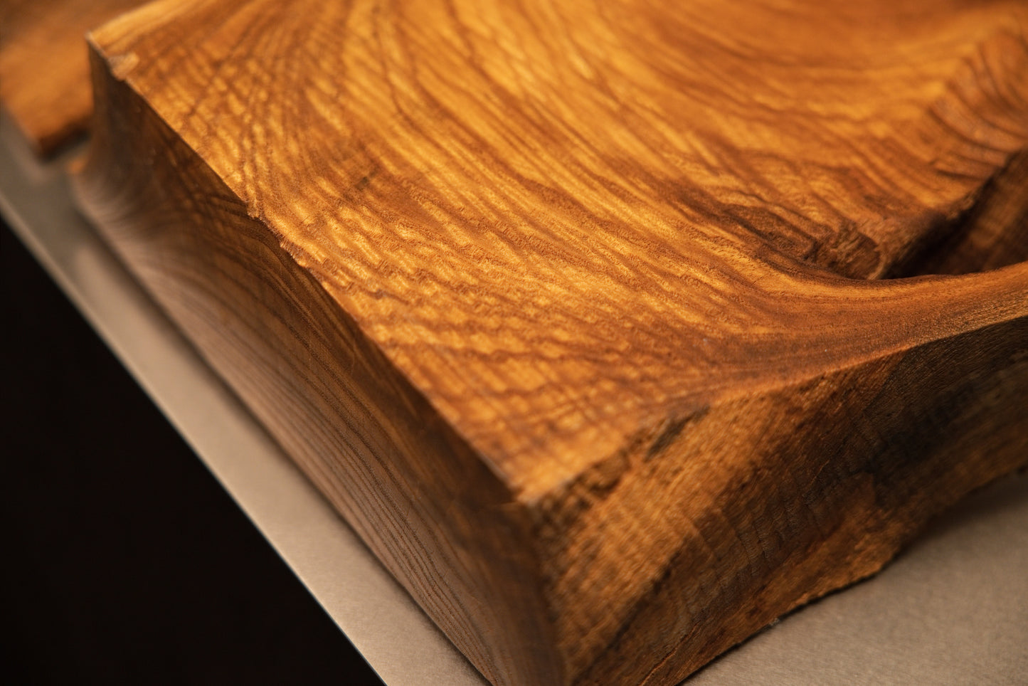 Detailed macro perspective capturing fine cross-grain textures and rich golden-brown highlights across the solid wooden block.