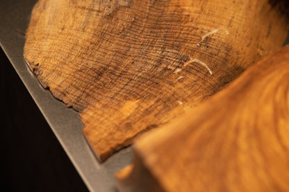 Close-up macro shot of end-grain wood textures displaying rich brown tones and natural growth rings resting near the metal base.