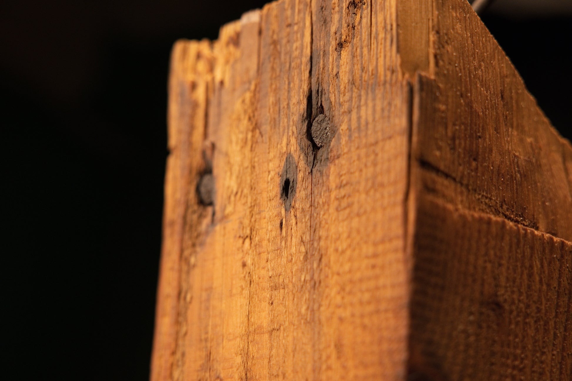 Close-up of the side profile on a relic-grade architectural timber featuring authentic dark knots and embedded antique joinery.   