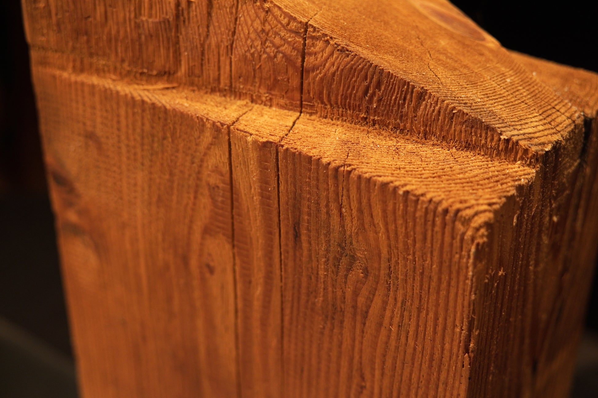 Detailed corner view of a thick-cut historic wooden monolith revealing high-density end-grain and century-old structural cuts.   