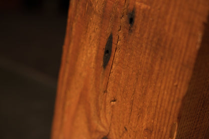 Close-up detail of a dark oxidized nail cavity on a thermally modified heritage beam highlighting authentic biological patina.   