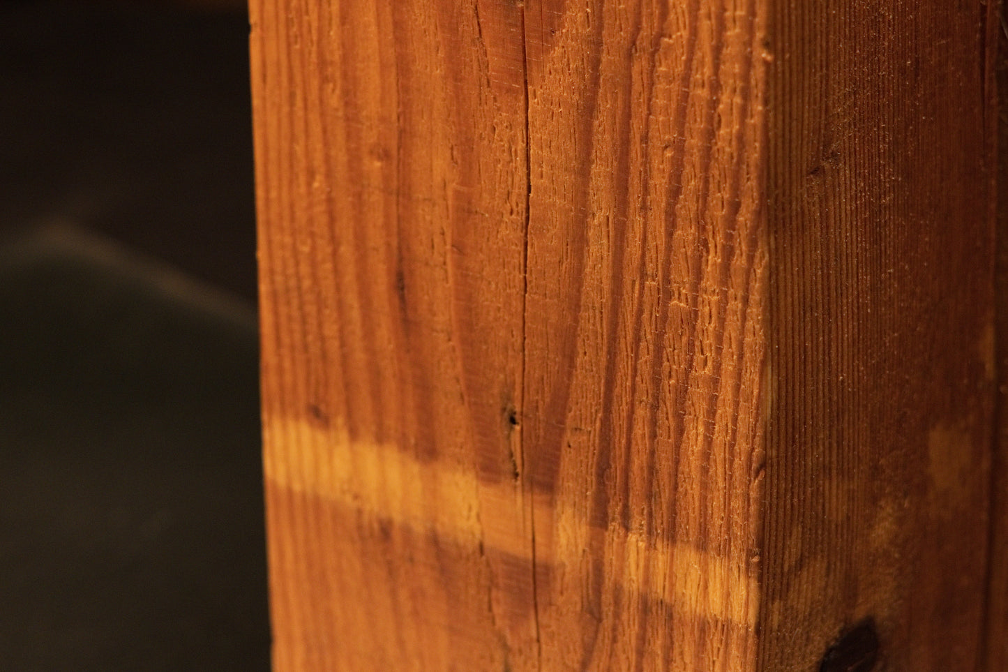 Macro focus on a distinct horizontal pigmentation band across the vertical grain of an authentic architectural salvage wood beam.   
