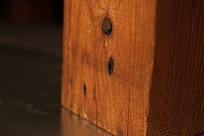Close view of authentic dark structural knots and joinery voids embedded in a fully stabilized architectural salvage timber beam.   