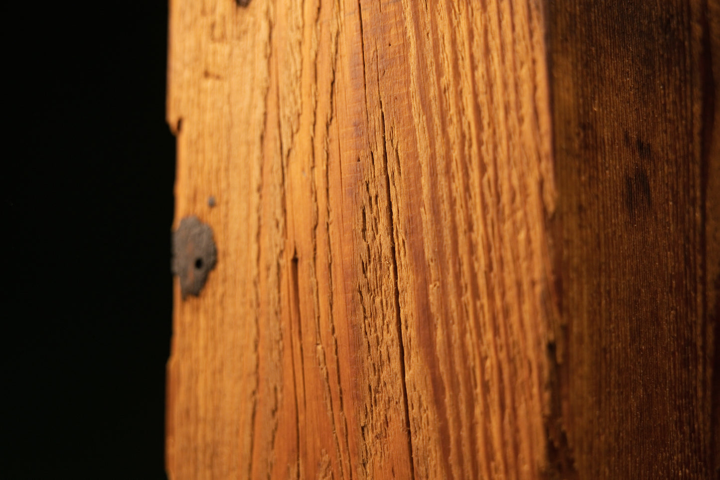 Macro detail of tight vertical grain and a small authentic dark knot embedded in a dimensionally stable historic wood beam.   