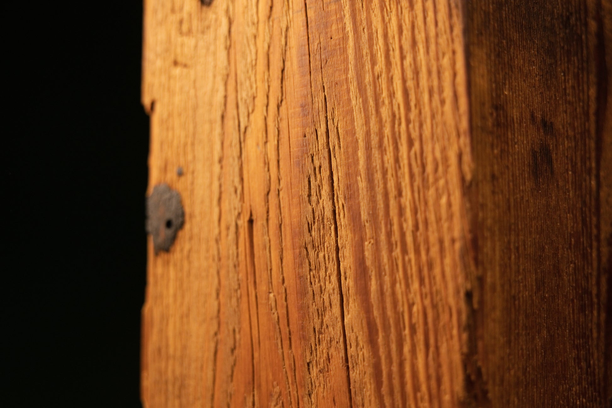Macro detail of tight vertical grain and a small authentic dark knot embedded in a dimensionally stable historic wood beam.   