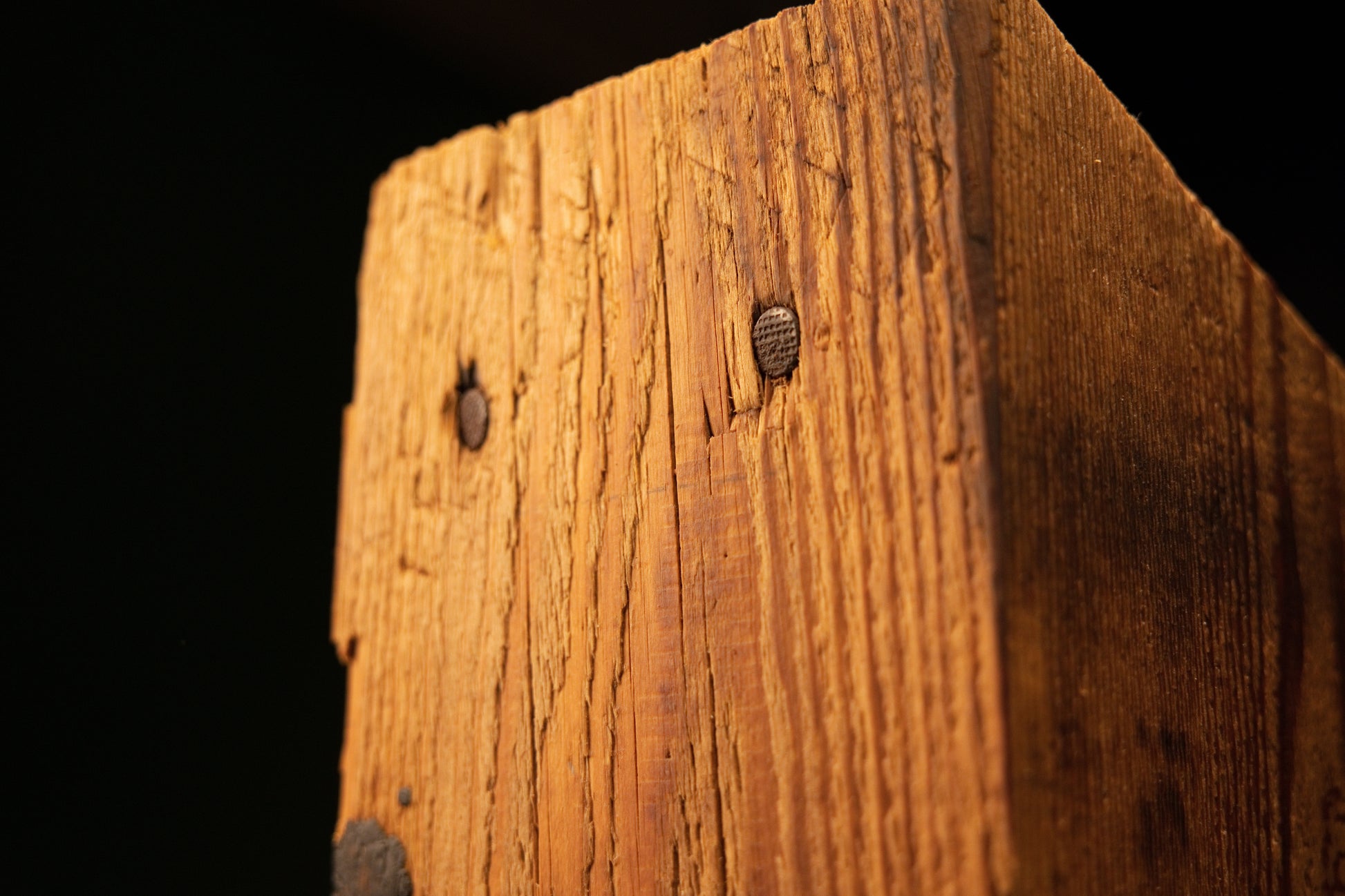 Extreme close-up of a dark circular knot on the upper edge of an epoxy-free biophilic structural beam for luxury interiors.   