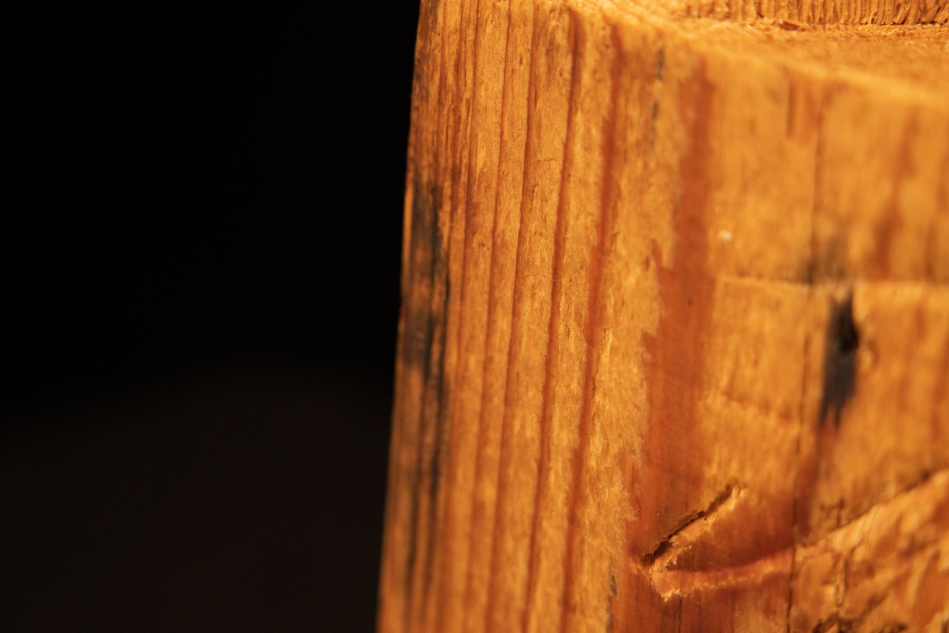 Detailed corner edge of a historic wood block showcasing extremely dense vertical grain and organic scoring.   
