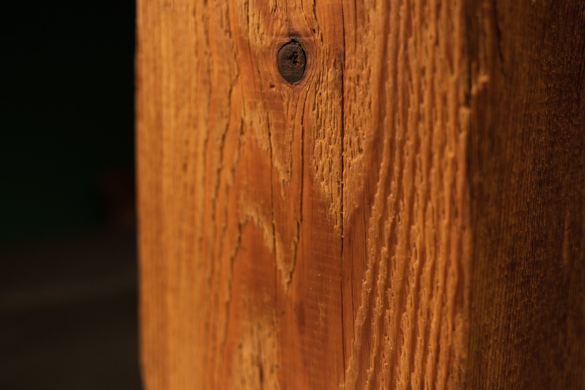 Macro detail of a small authentic dark knot located near the upper center of a meticulously preserved architectural wood beam.   