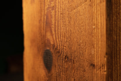Macro detail of a large prominent dark knot near the base of an epoxy-free historic wood beam showing raw botanical textures.   