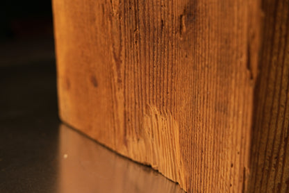 Close detail of a historic tool mark scar near the base of a century-old structural timber beam preserved for luxury interiors.   