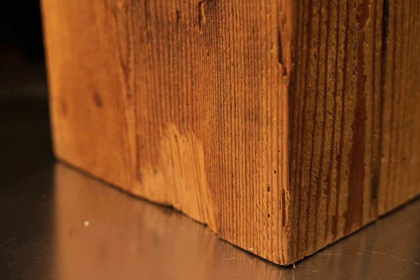 Macro detail of the lower edge on an authentic architectural salvage beam highlighting deep microporous finish and tight grain.   