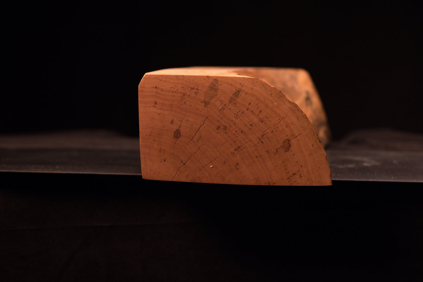 Angled macro of the architectural wood end-grain showcasing tight historic growth rings and a seamlessly integrated small knot.   