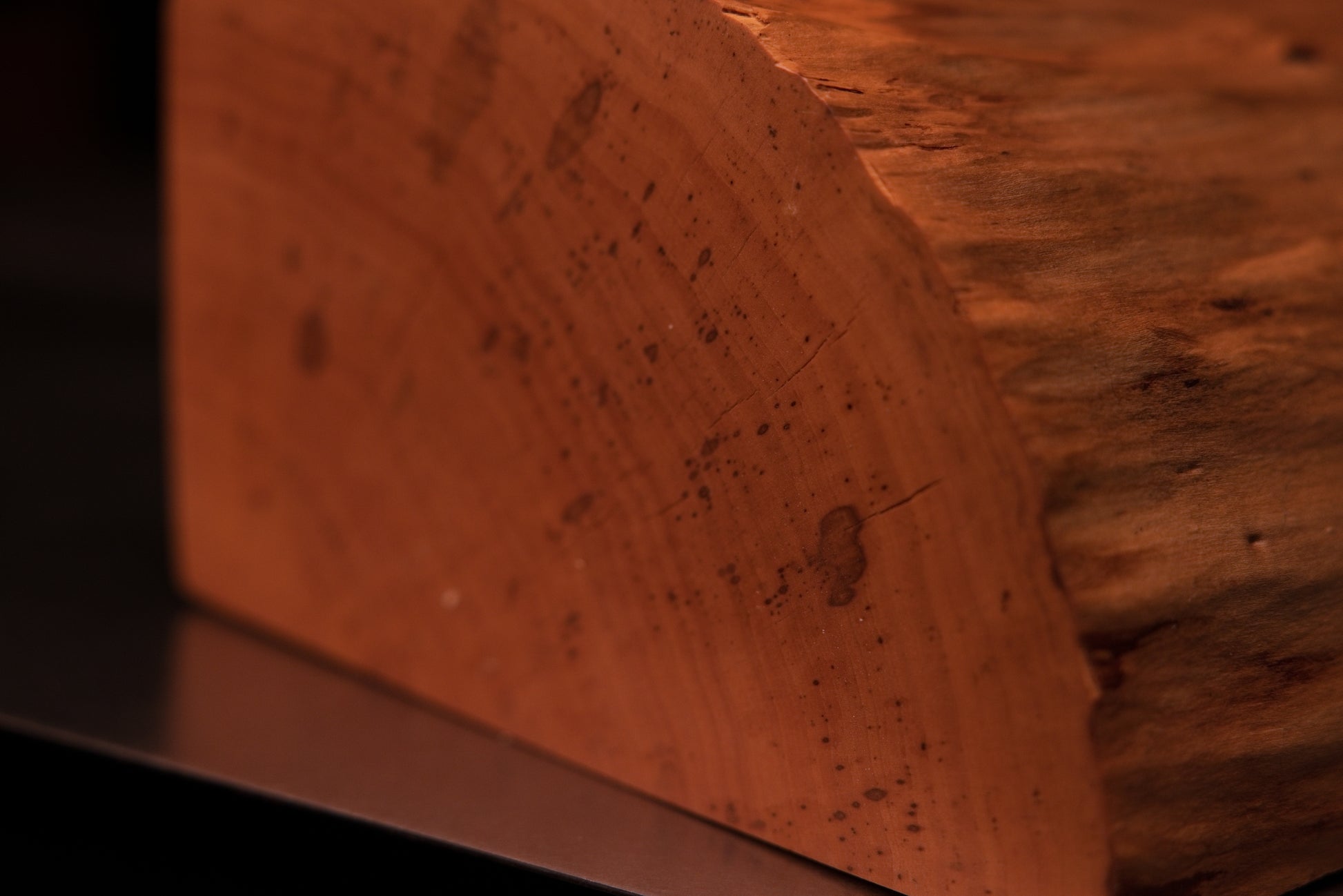 Close-up of the precise edge transition on a structural wooden element revealing dense botanical wood grain.   
