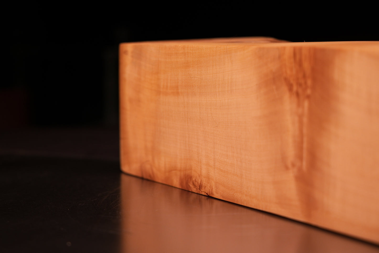 Horizontal close-up of a smooth architectural timber surface highlighting an organic grain distortion and deep organic patina.   