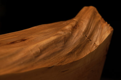 Sharp top corner profile of a structural wooden element revealing dense grain and precision architectural cut.   