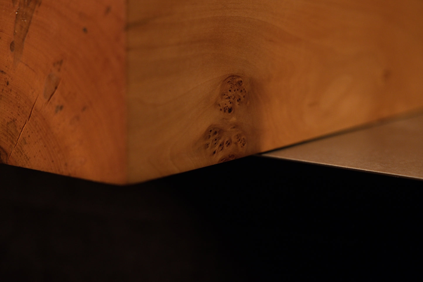 Extreme macro of tight birdseye grain clusters on a polished biophilic wood surface highlighting unique organic textures.   