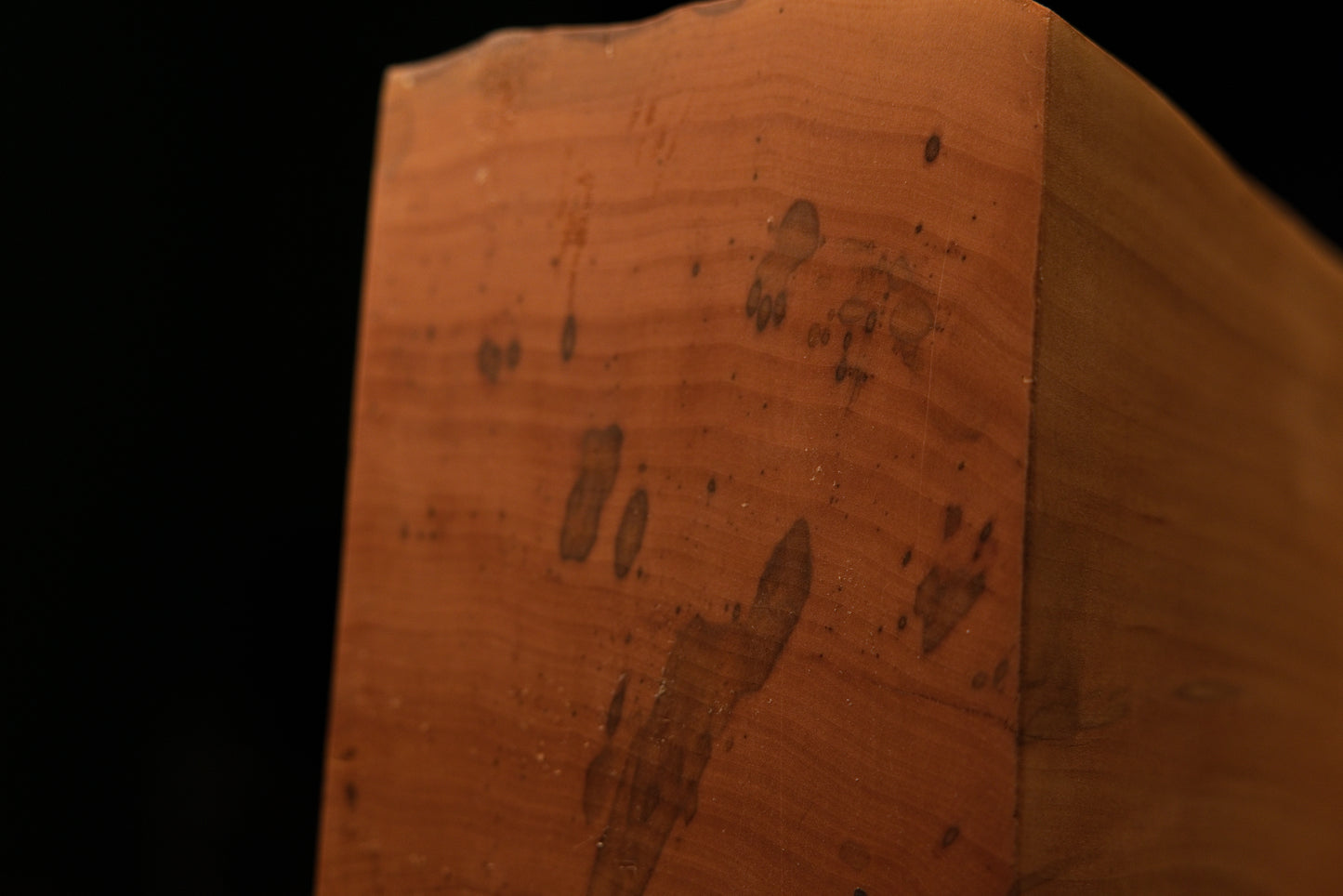 Lower corner perspective where the smooth flat face meets the dark flowing organic edge of the stable architectural timber.   