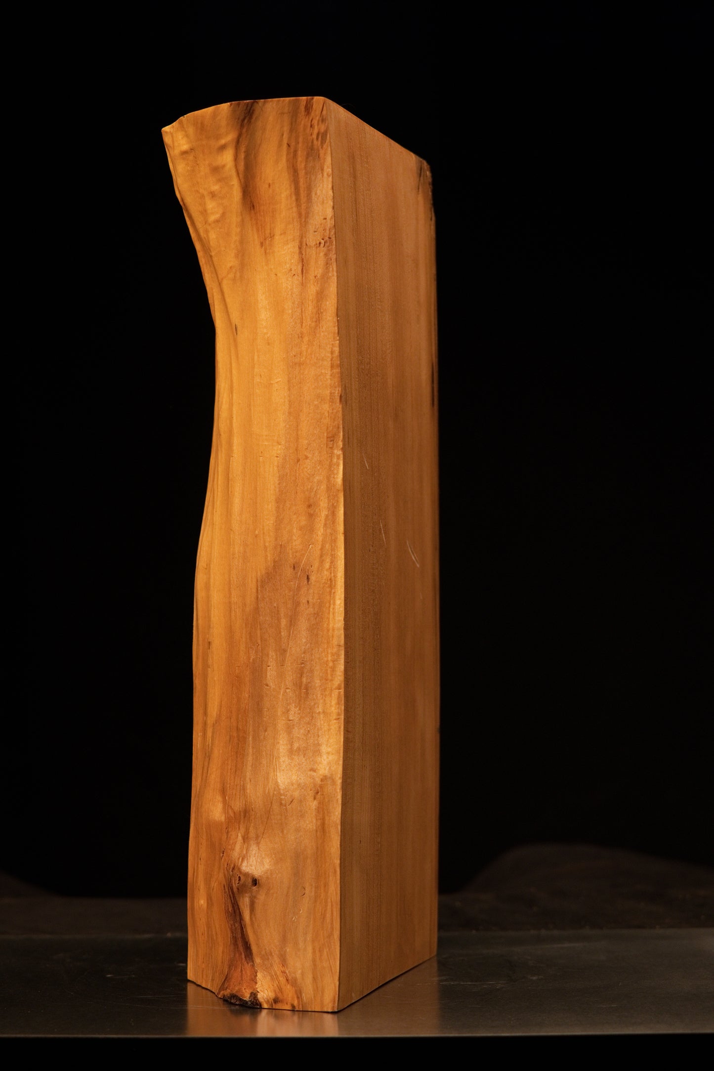 Macro focus on a dark joinery void and adjacent birdseye cluster within the smooth surface of a Relic-Grade wooden monolith.   