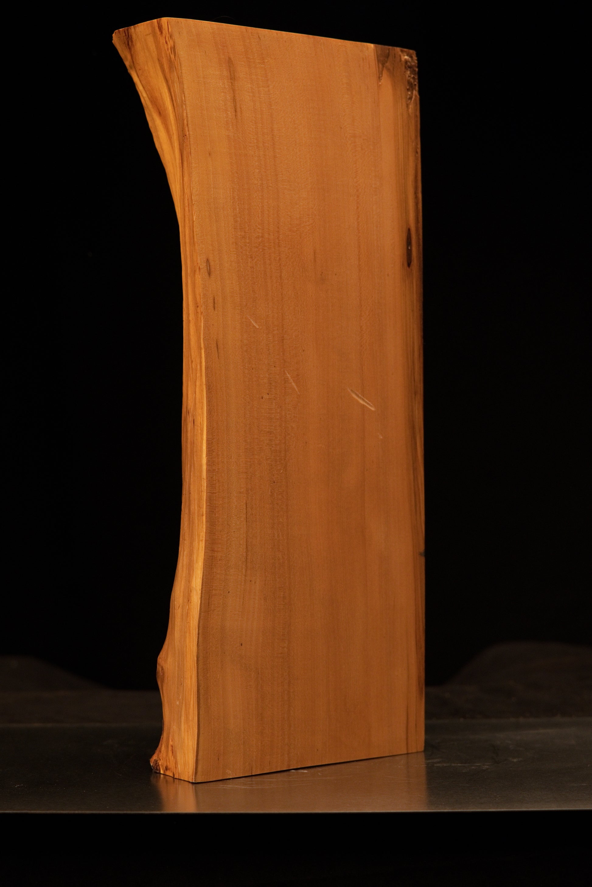Detailed view of the lower sculpted corner on a floor-heating compatible botanical wood piece showing a small embedded knot.   