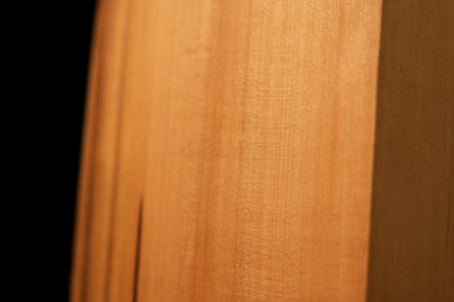 Macro photography of wavy golden grain and authentic chatoyancy on the polished surface of a heritage structural wood slab.   