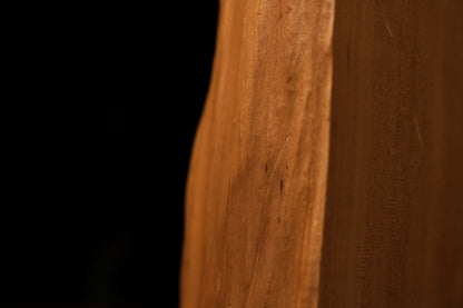 Lower section macro of the sculpted architectural wood block revealing deep cellular grain patterns and a dark organic knot.   