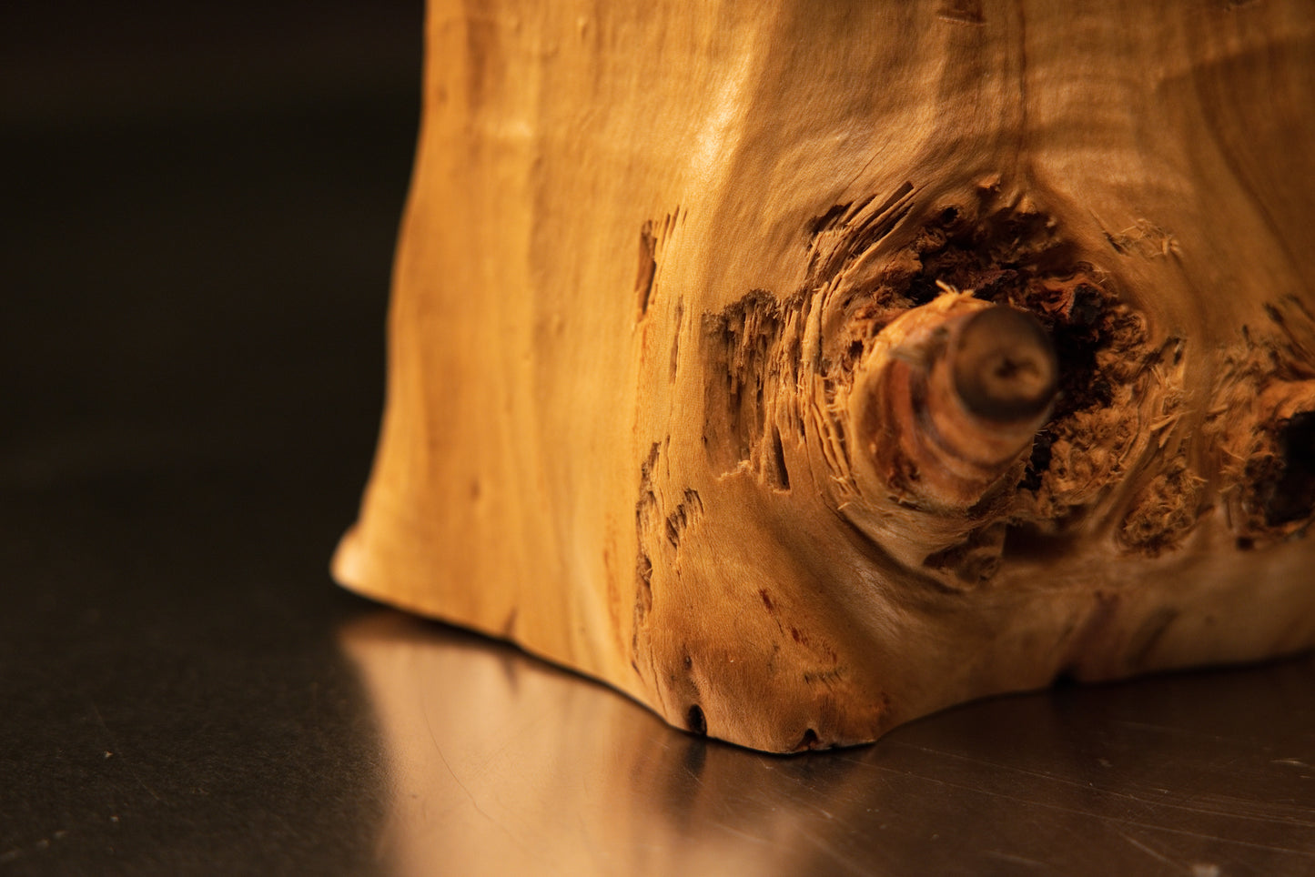 Detailed close-up macro view of the precision-cut top horizontal surface meeting the rugged textured burl face of the sculpture.   