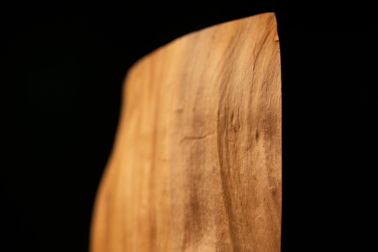 Macro detail of the lower edge on an authentic architectural salvage beam highlighting a dark burl cluster and tight organic grain.   