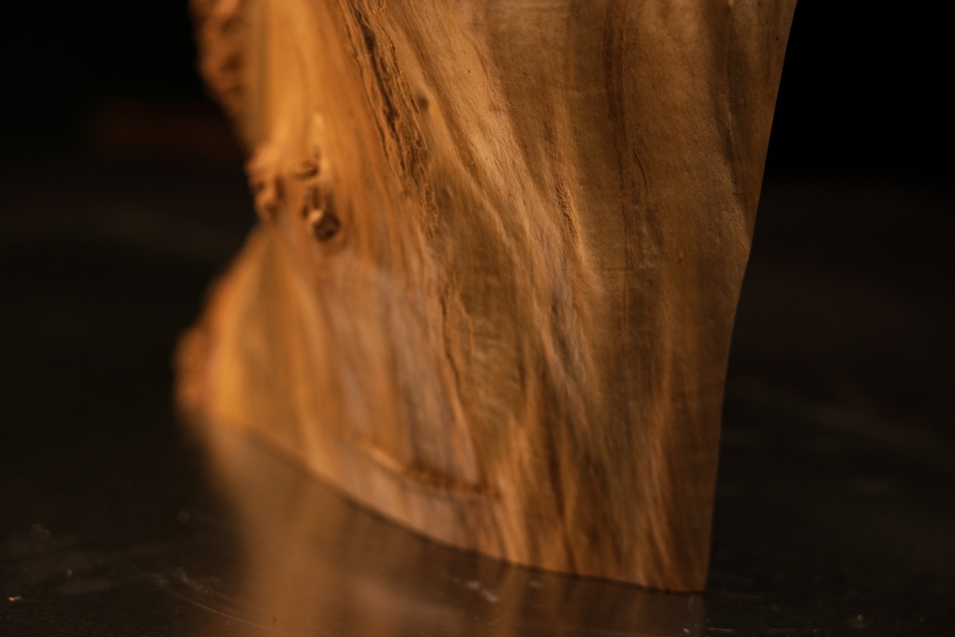 Macro detail of a smooth projecting knot on a flat polished architectural wood face revealing deep cellular thermal stabilization.   
