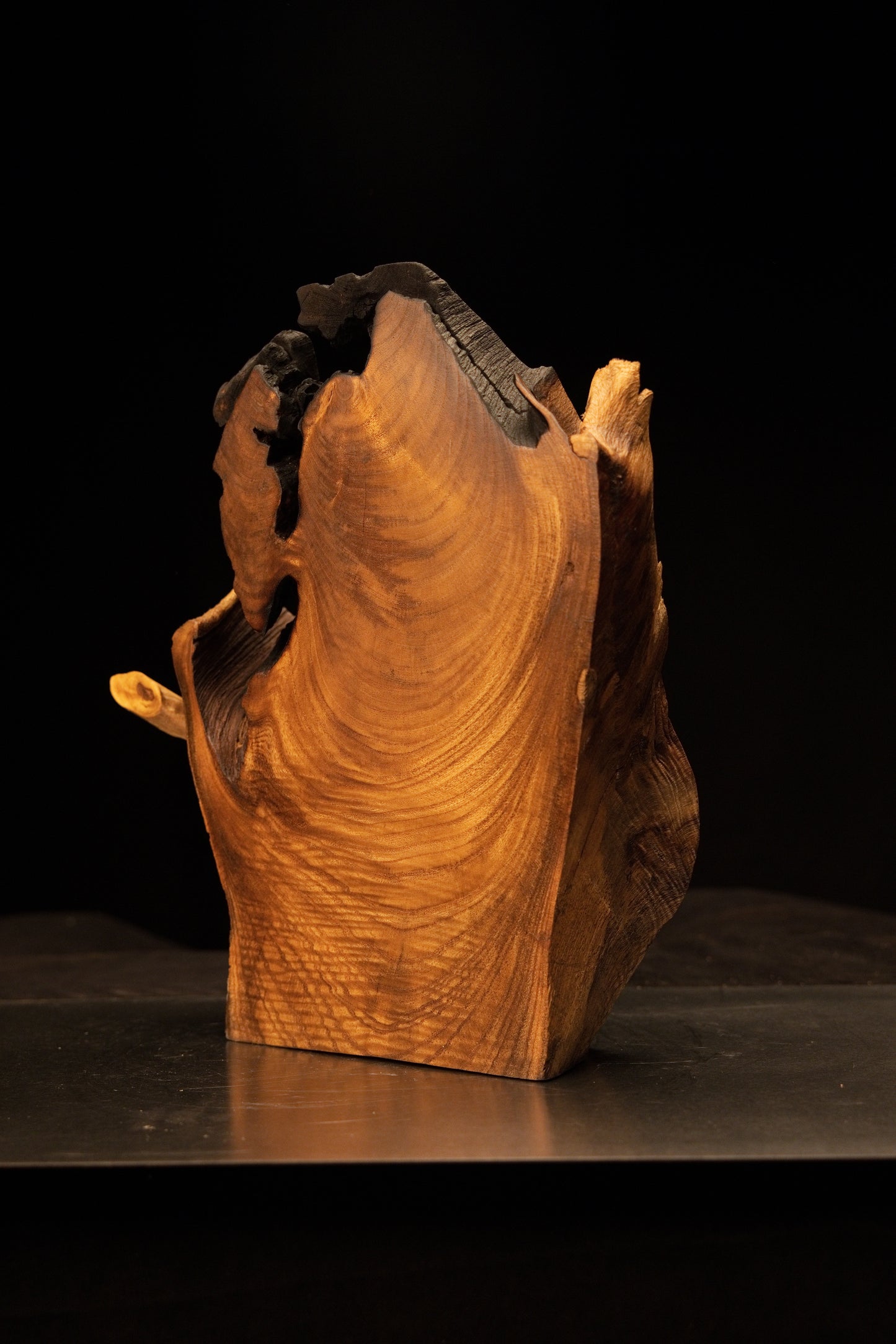Close-up on a blackened upper corner edge blending smoothly into bright, highly polished golden hardwood textures.   