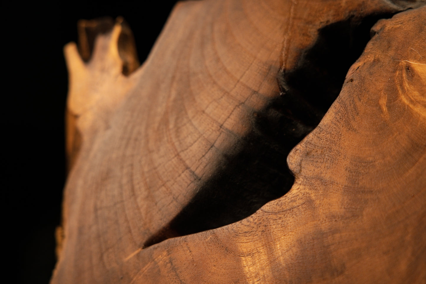 Precision top corner view highlighting an irregular dark upper cavity on a luxury interior wooden decorative object.   