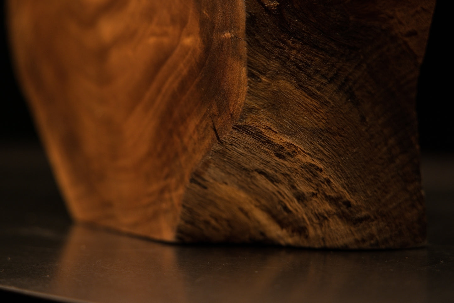 Profile view of a cylindrical wooden extension reaching out from a dark inner shadow within the sculpted display.   